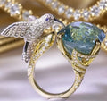 Ocean blue topaz hummingbird open ring with real gold coloured brass finish and adjustable opening.