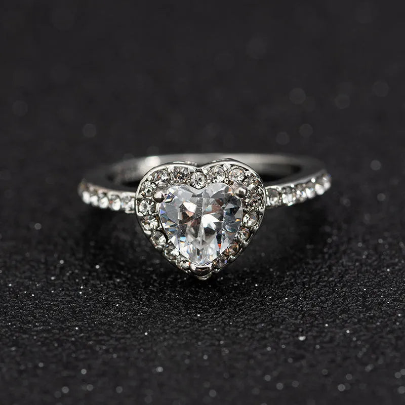 Women's heart-shaped crystal wedding ring in rose gold or silver on a white background.
