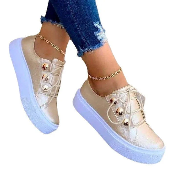 Women's white lace-up flats sneakers with decorative rivets on the artificial leather upper.