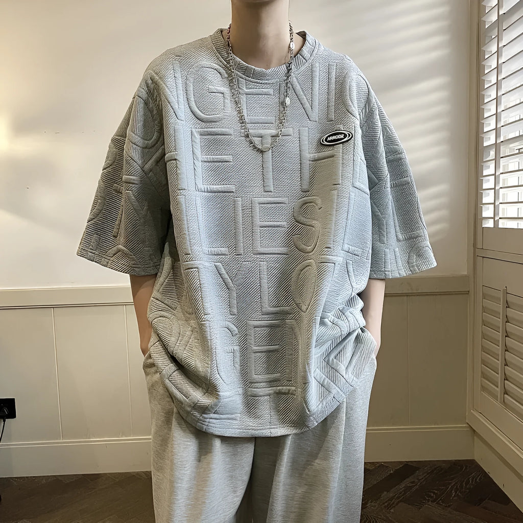 Men's grey loose fit short sleeve t-shirt with a raised white retro letter pattern on the chest.
