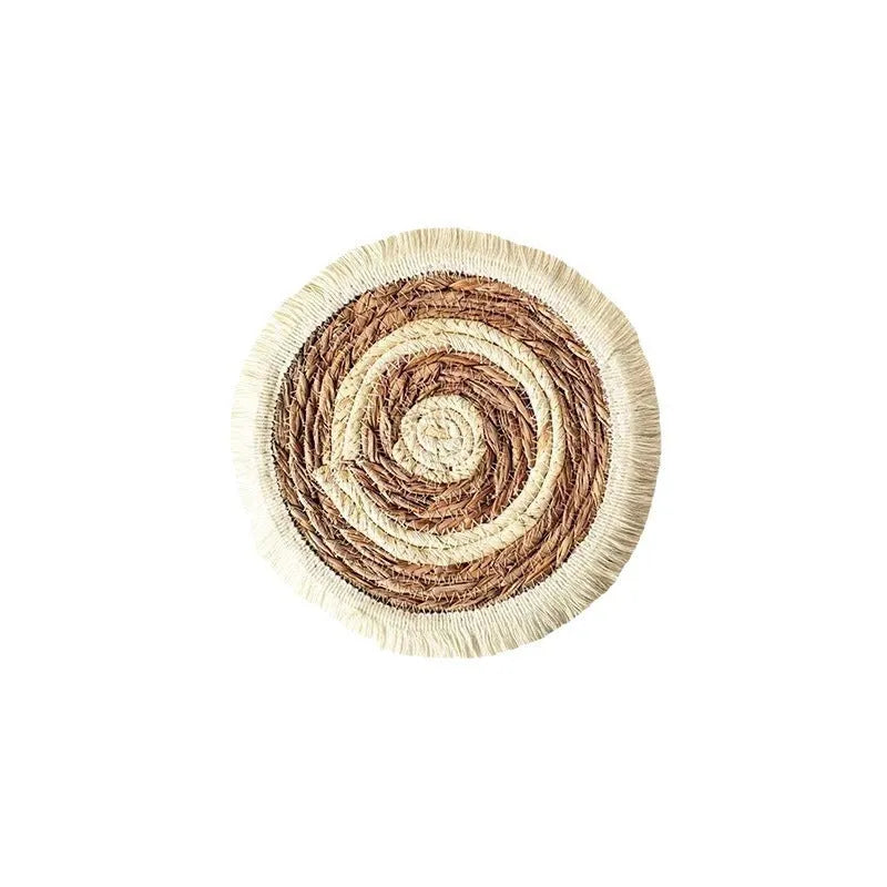 Round natural papyrus straw placemat with tassel detailing on a table.