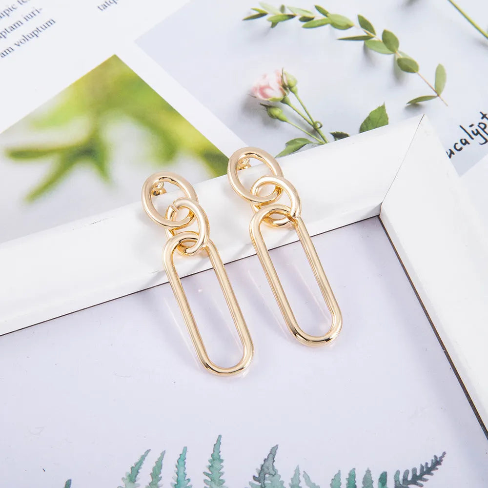 Geometric sterling silver needle hoop earrings with a line and ring design on a model.