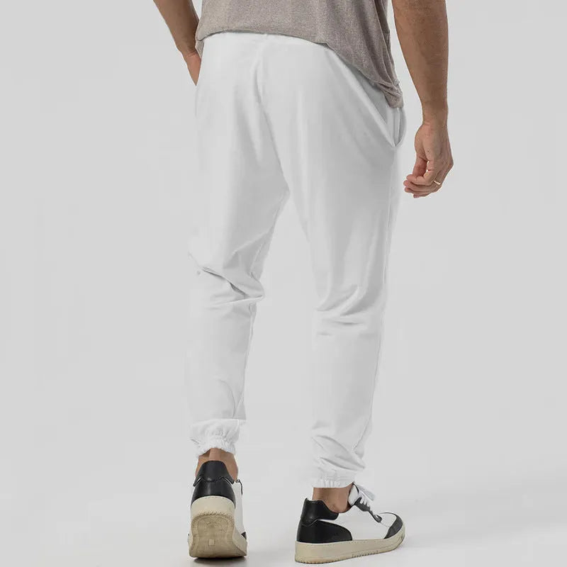 Man wearing grey loose tapered track sweatpants with a straight-leg design and elasticated waist.