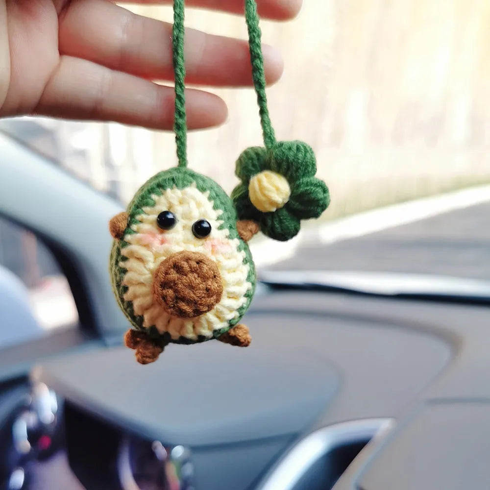 Handmade crocheted car pendant featuring a colourful avocado and rainbow flower design in wool yarn.
