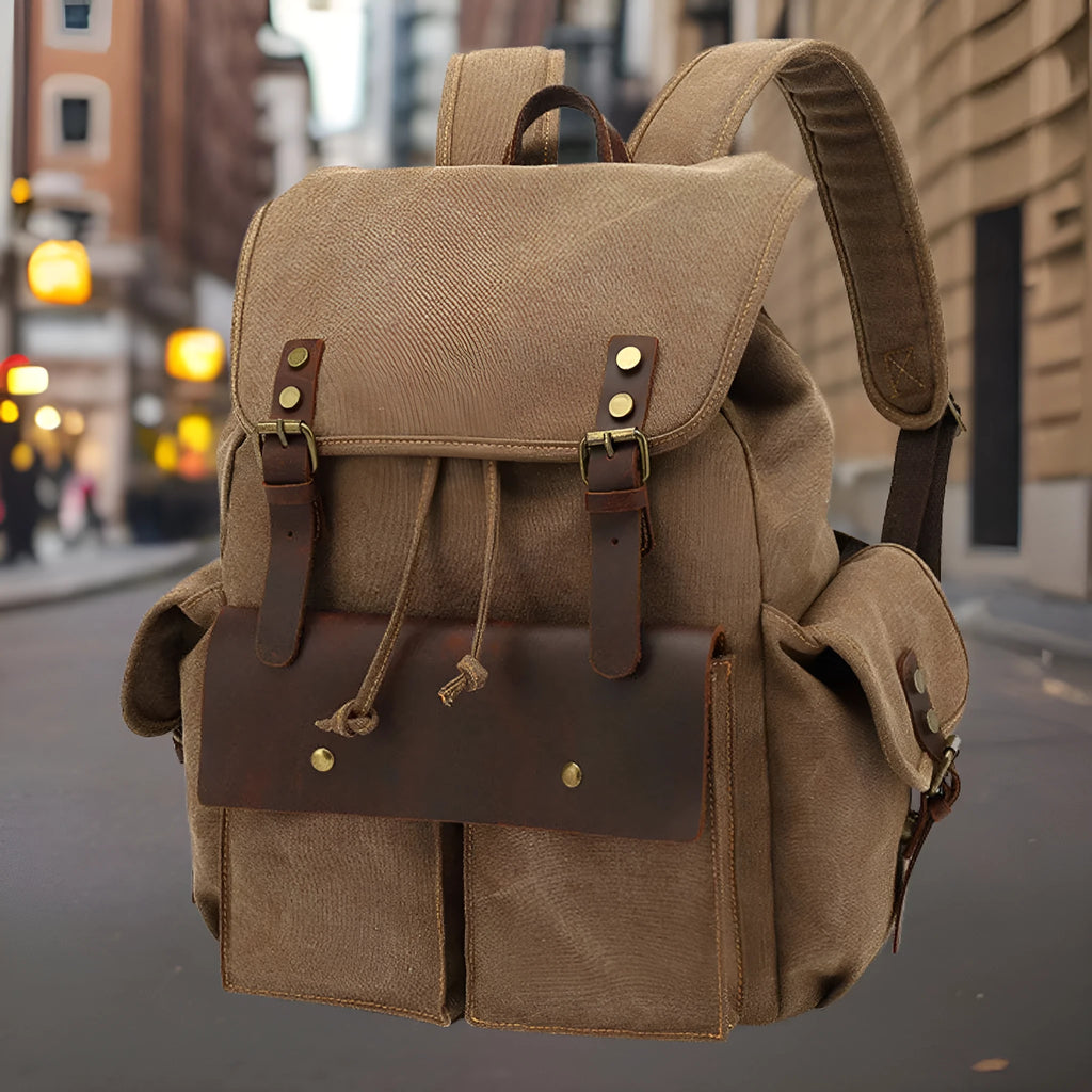 Retro-style canvas backpack in military green with antique bronze hardware, shown with a 16-inch laptop.