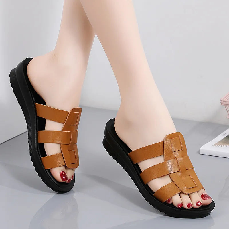 Beige women's flat-bottom slippers with waxed leather upper and soft PU sole on a wooden floor.