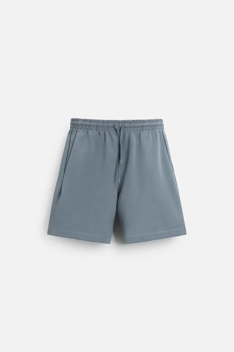 Man wearing a loose blue short sleeve top and matching shorts from a textured polyester casual set.