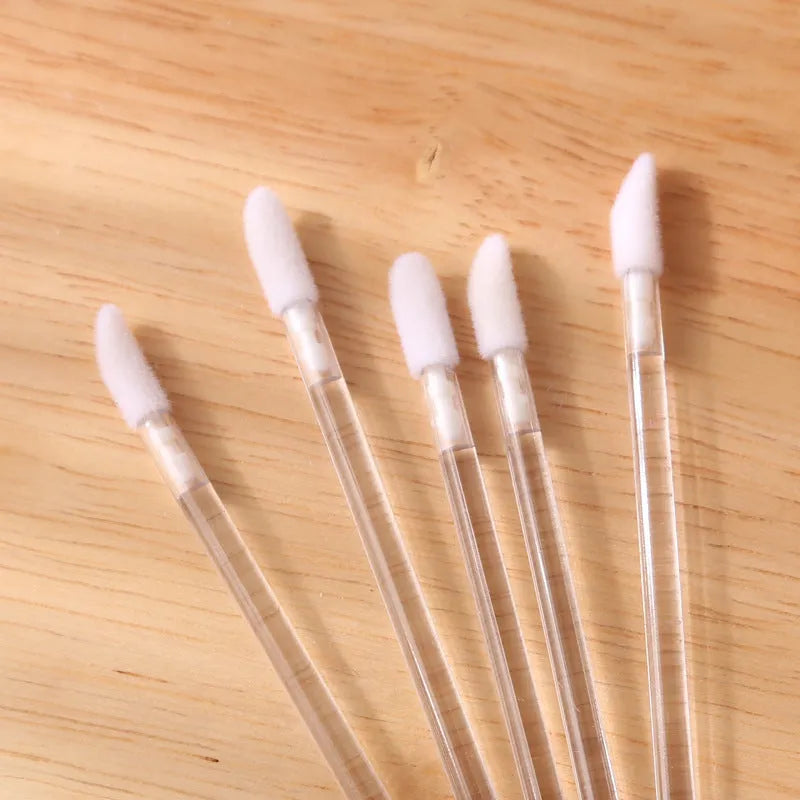 Pack of disposable lip brushes with flocked cotton heads and black plastic handles.