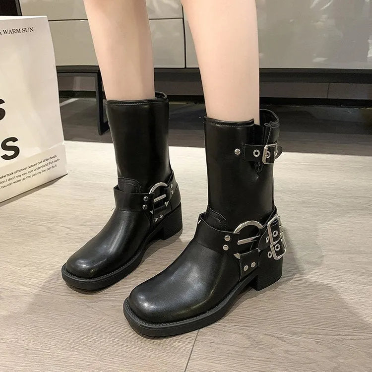 Women's black platform boots with buckle decoration at mid-calf height on a neutral background
