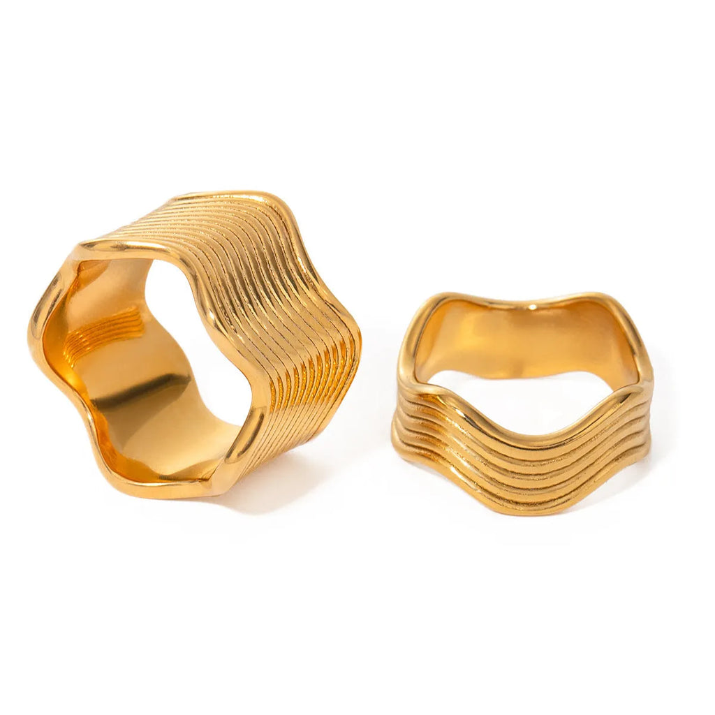 A geometric wide-band stainless steel ring with a wave design, shown in a polished silver tone.