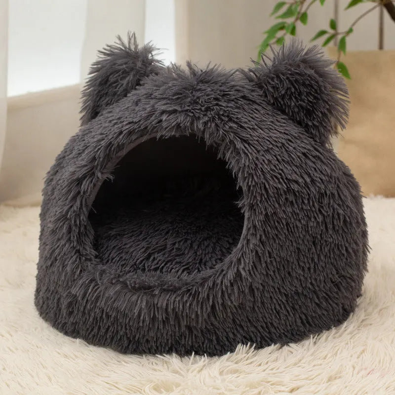 Large semi-closed flannel cat nest in dark gray on a floor, with soft plush interior visible