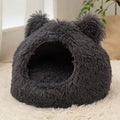 Large semi-closed flannel cat nest in dark gray on a floor, with soft plush interior visible
