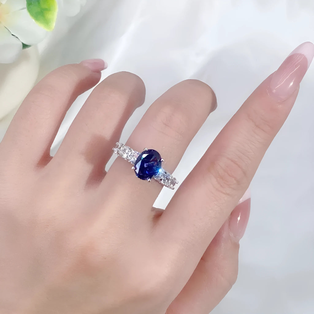 Close-up of a sterling silver heart-shaped ring with a floral-cut blue zircon stone.