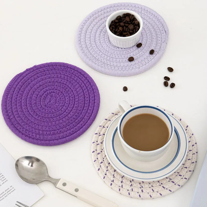 Three round cotton cord coasters in coordinating colours on wooden table