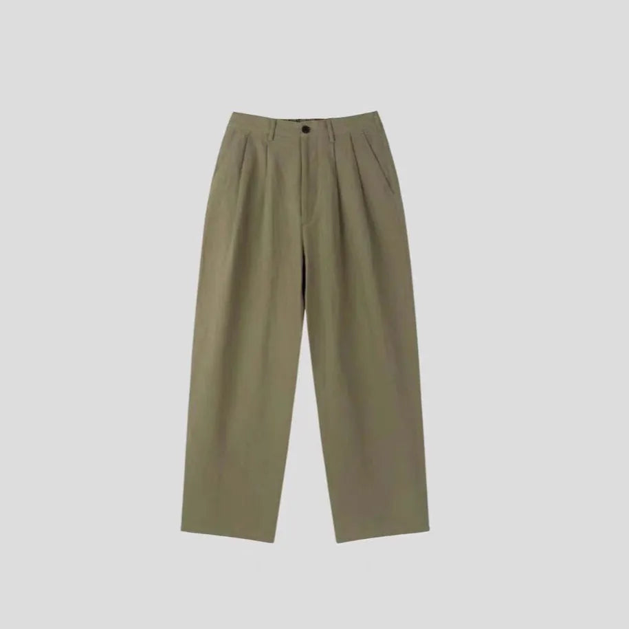 Man wearing loose apricot wide-leg cotton linen blend trousers with a pencil-leg opening.