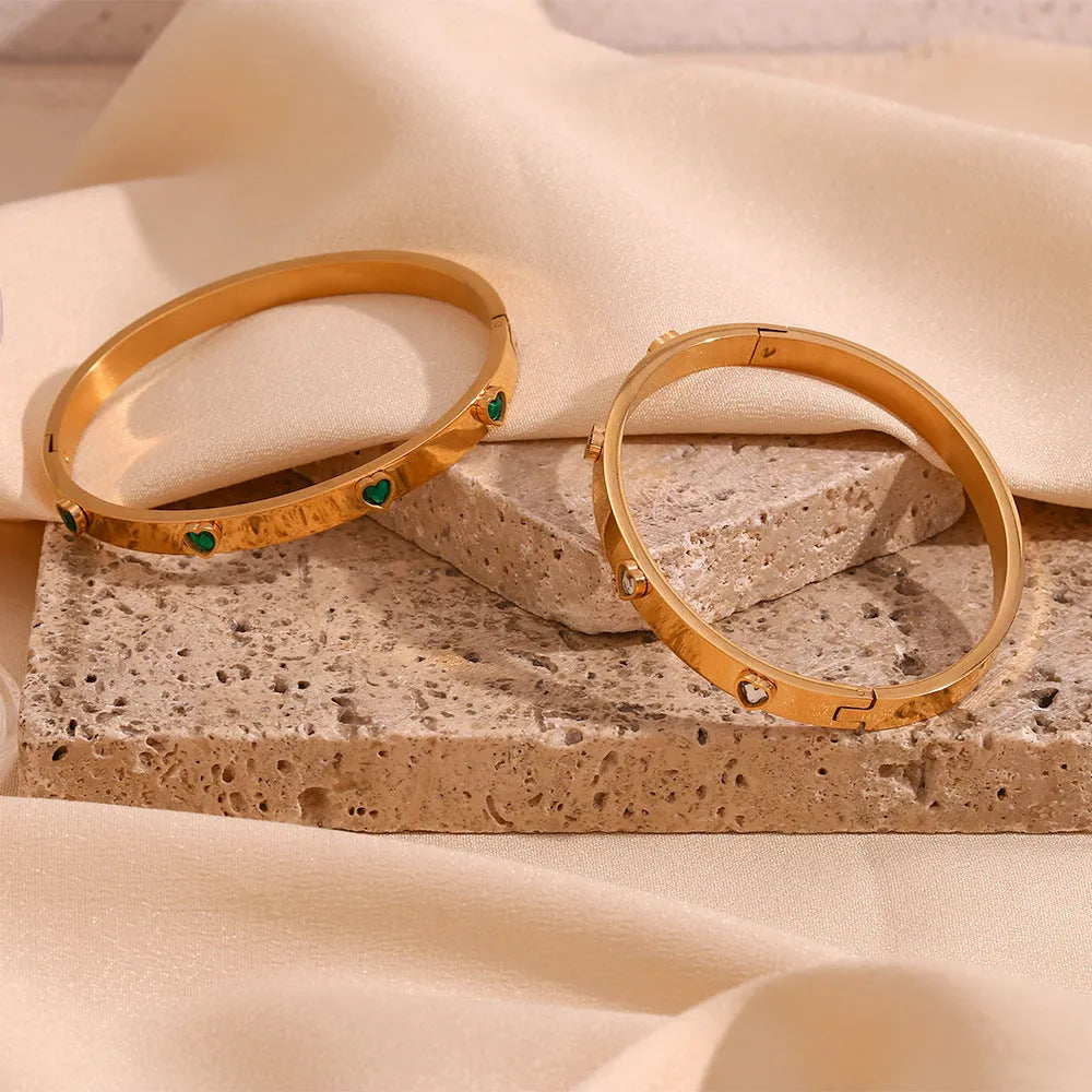 A stainless steel bracelet with a micro-inlaid peach heart charm in green or white diamond colour.