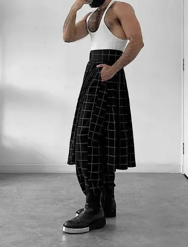 Man wearing grey plaid trousers with a distinctive apron-style waistband, showing the tartan pattern and zip fly.