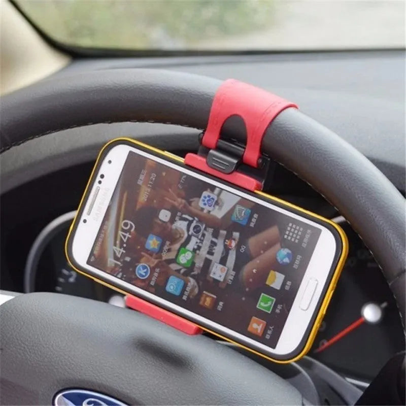 Black steering wheel phone mount holder clipped to a car wheel, holding a large smartphone.