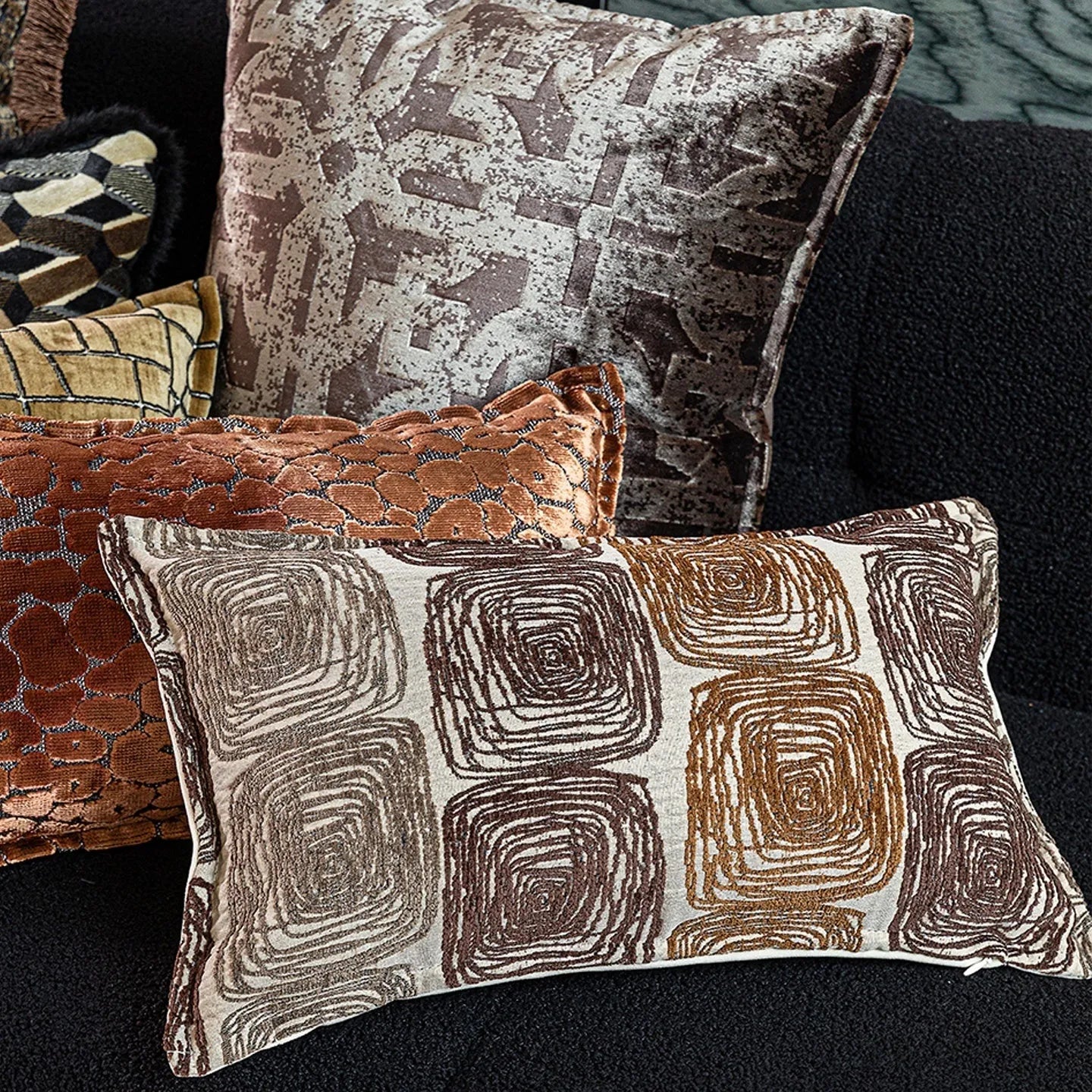 Square and rectangular decorative cushion covers with an abstract coil pattern in cream and coffee brown colours.