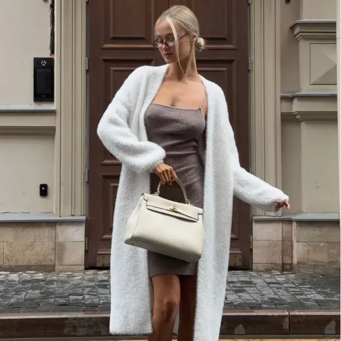 White loose-fit knitted cardigan jacket with long sleeves on a hanger.