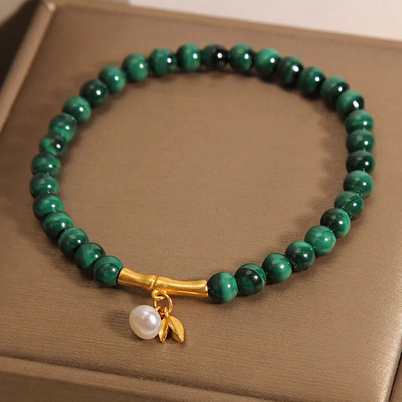 Close-up of a women's white crystal bracelet with a lucky bamboo charm on an elasticated band.