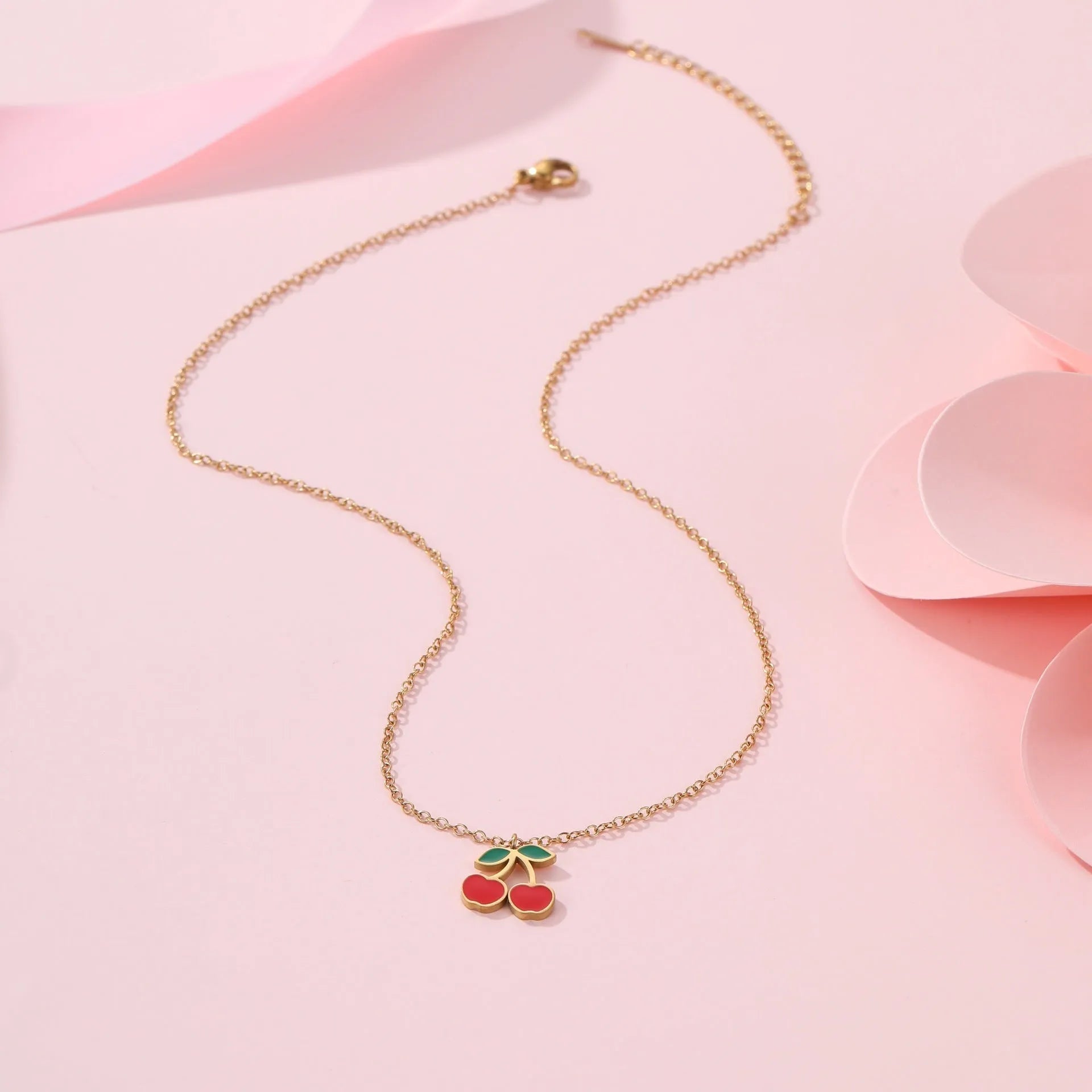 Cherry motif stainless steel jewellery set with gold plating, showing necklace, bracelet, earrings, and ring.