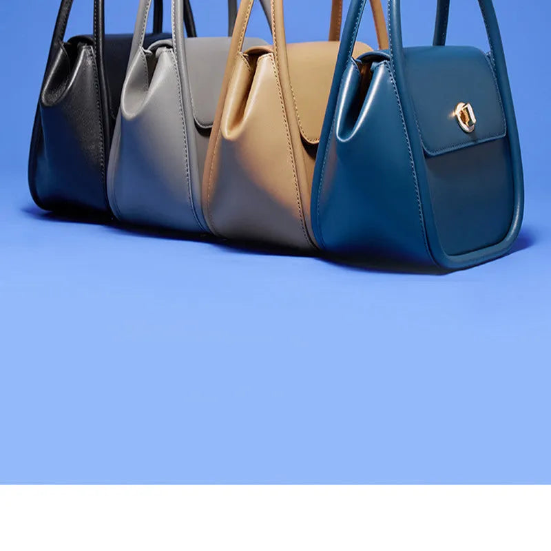 Women's winged leather handbag with cross-body strap in blue, showing latch closure and buckle detail.