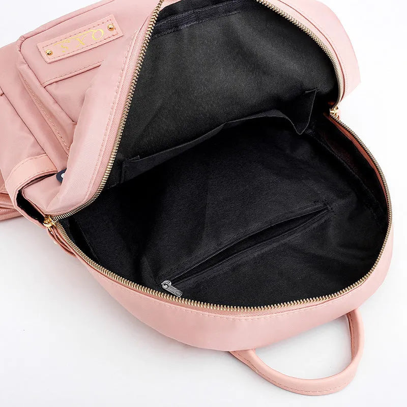 Women's black casual nylon backpack with double straps and a front pocket, shown next to a pink version.