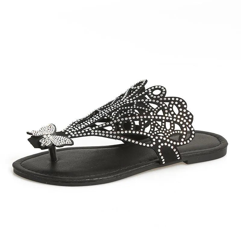 Women's black slip-on sandals with rhinestone decoration and flip-toe design on a white background.