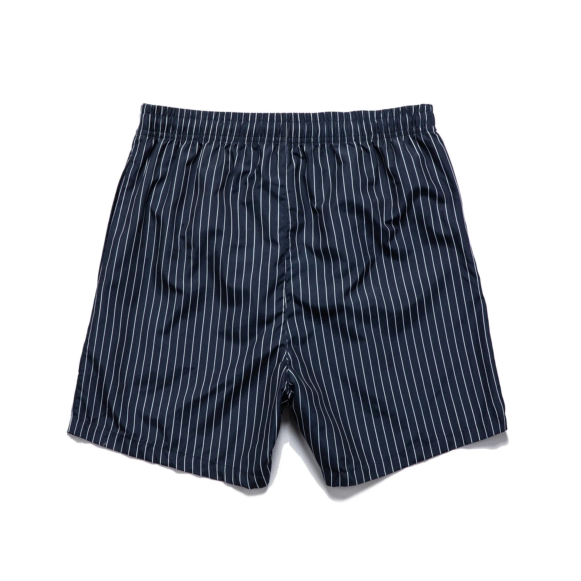 A man wearing grey striped polyester beach shorts with a straight leg opening, shown on a beach.