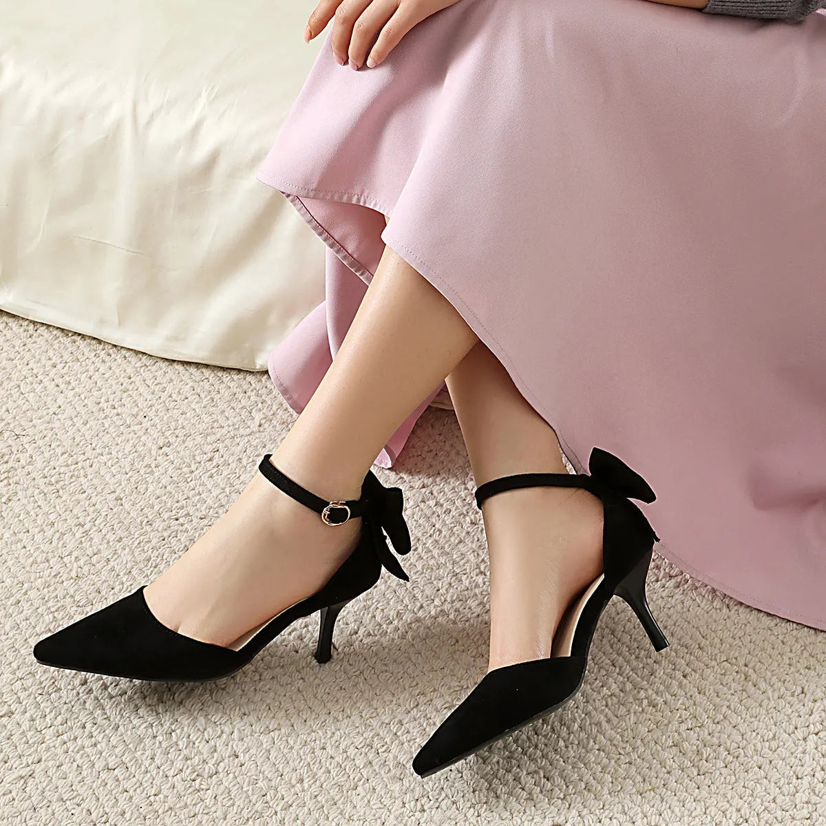Beige suede pointed-toe stiletto heels with a decorative bowknot and buckle fastening.