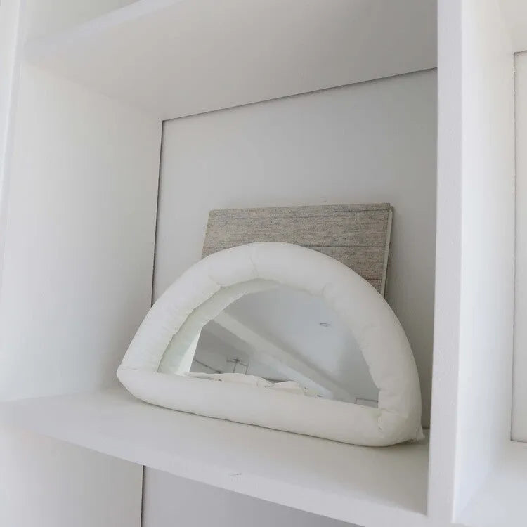 White cotton-filled PVC fabric mirror hanging on wall measuring 23x40x5cm