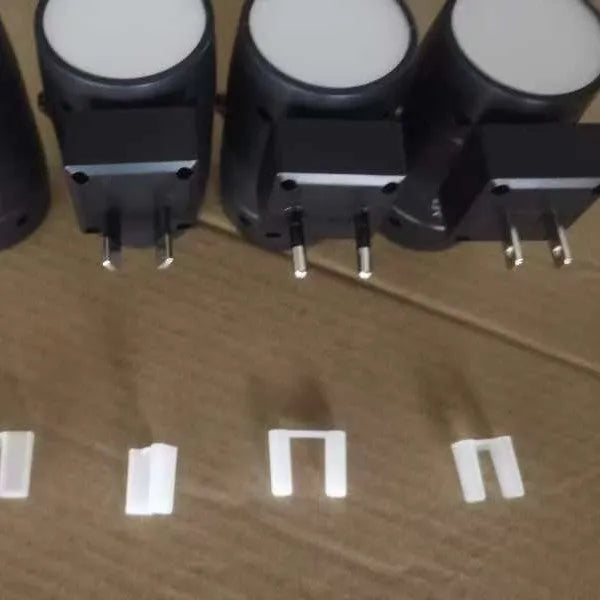 Small white plug-in night lamp with adjustable head shown in a UK wall socket