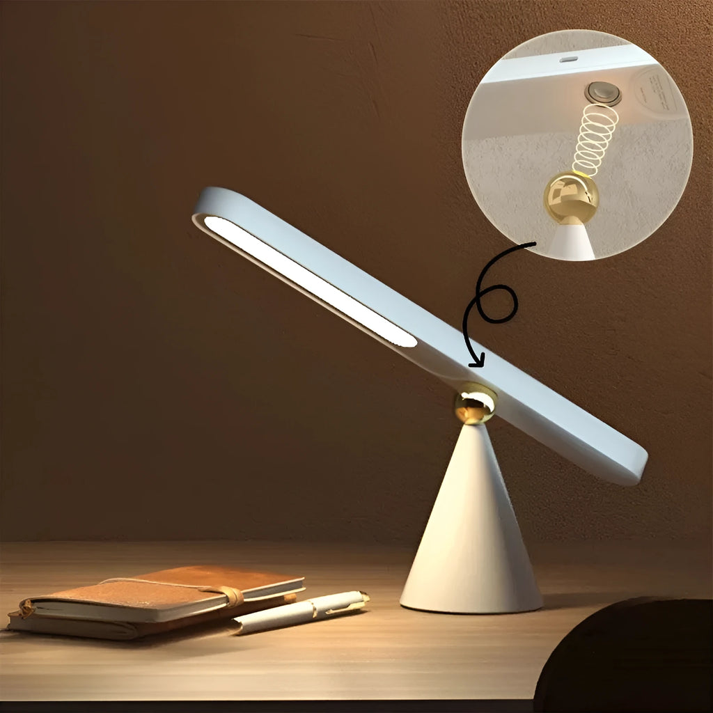 Geometric shaped white desk lamp with a magnetic base on a wooden table next to a book.