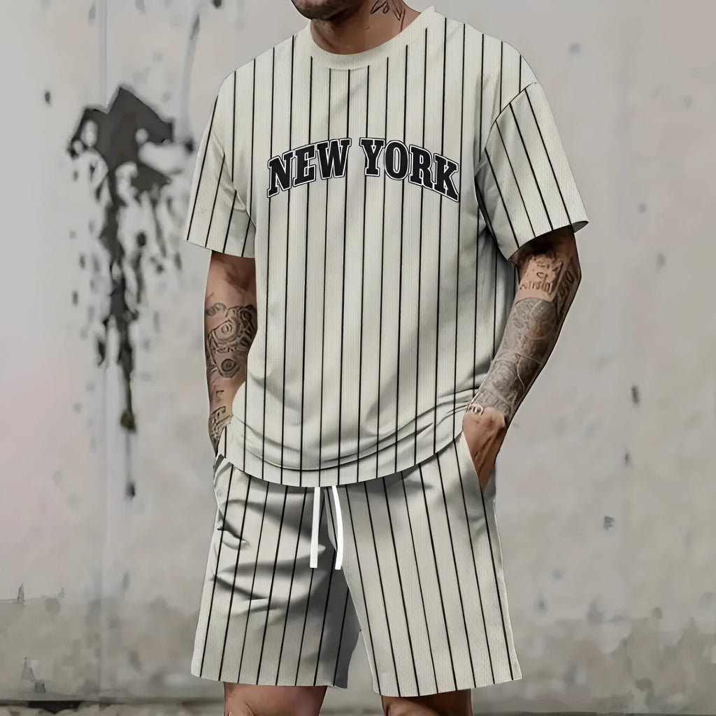 Man wearing a grey 3D printed letter short sleeve top and matching shorts from a sports co-ord set.