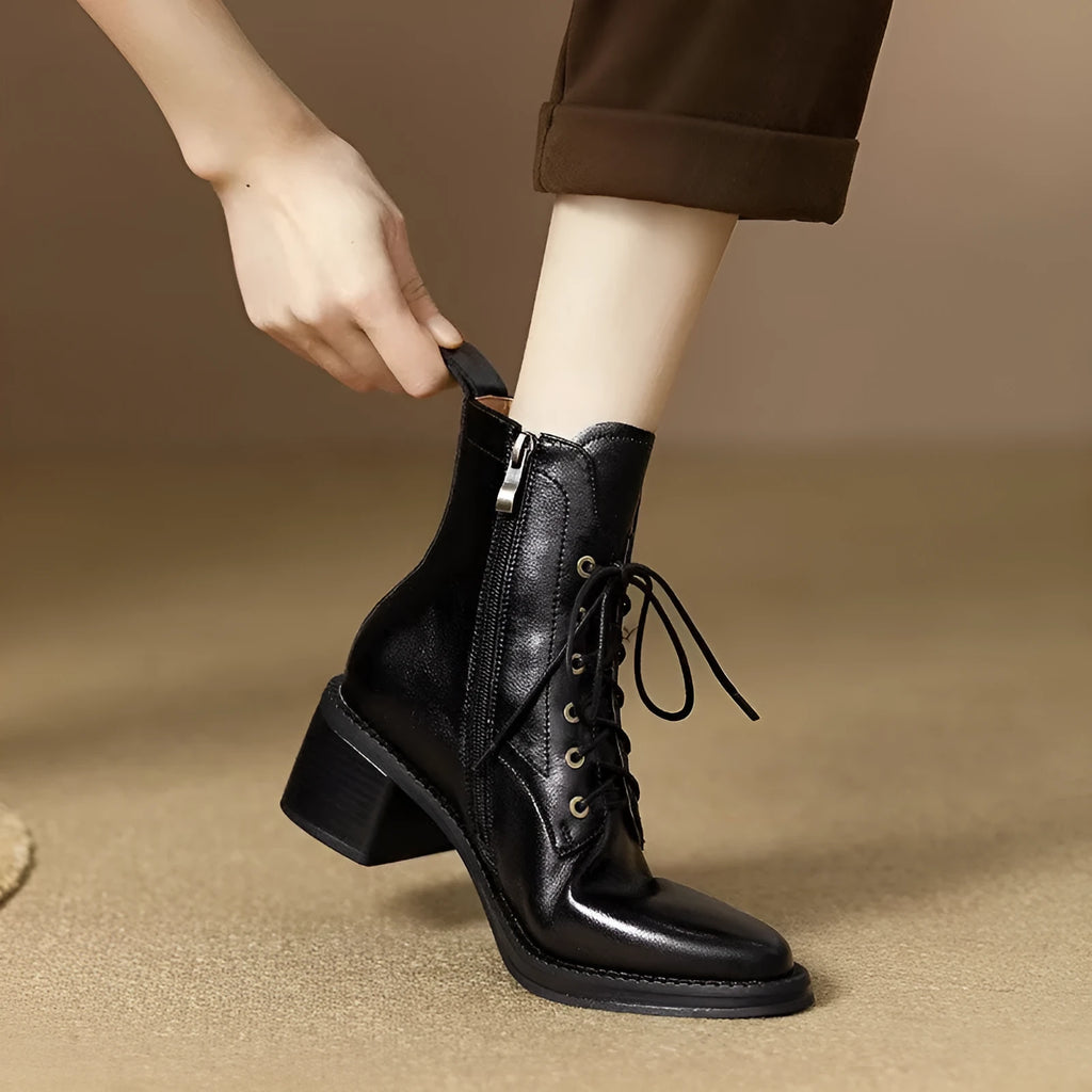 Women's black pointed-toe ankle boots with a low heel on a plain background.