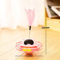 Pink plastic cat tumbler turntable toy with stick and ball on a flat surface.
