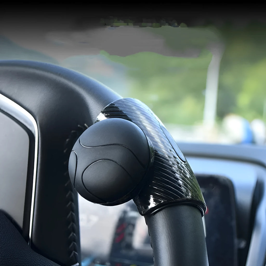 Black and blue silicone steering wheel assist ball for single-handed driving on a car steering wheel.