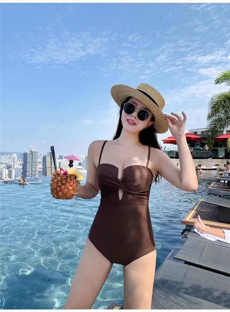Women's solid colour spaghetti strap one-piece swimsuit with push-up design in white, pink, or brown.