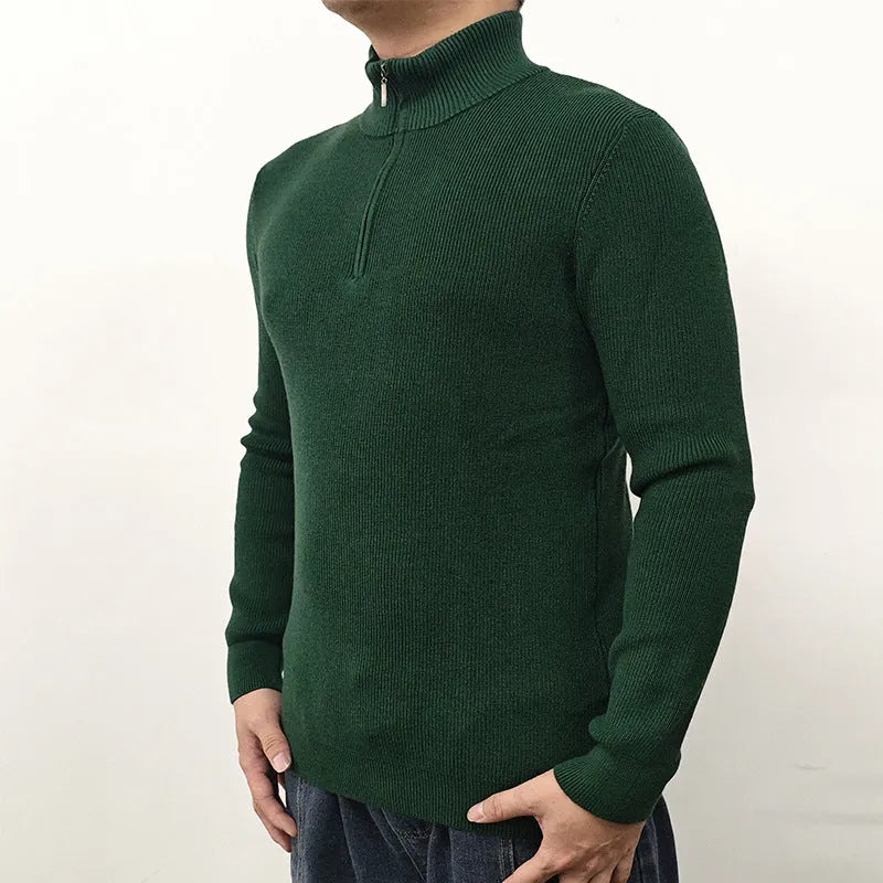 Man wearing a grey half-turtleneck zip-up sweater, showing the front zipper and long sleeves.