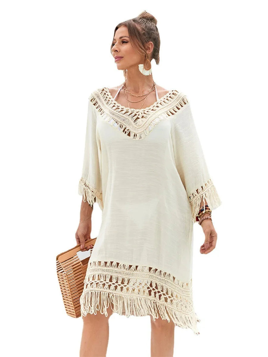 Apricot coloured long hand-crocheted beach dress on a hanger.
