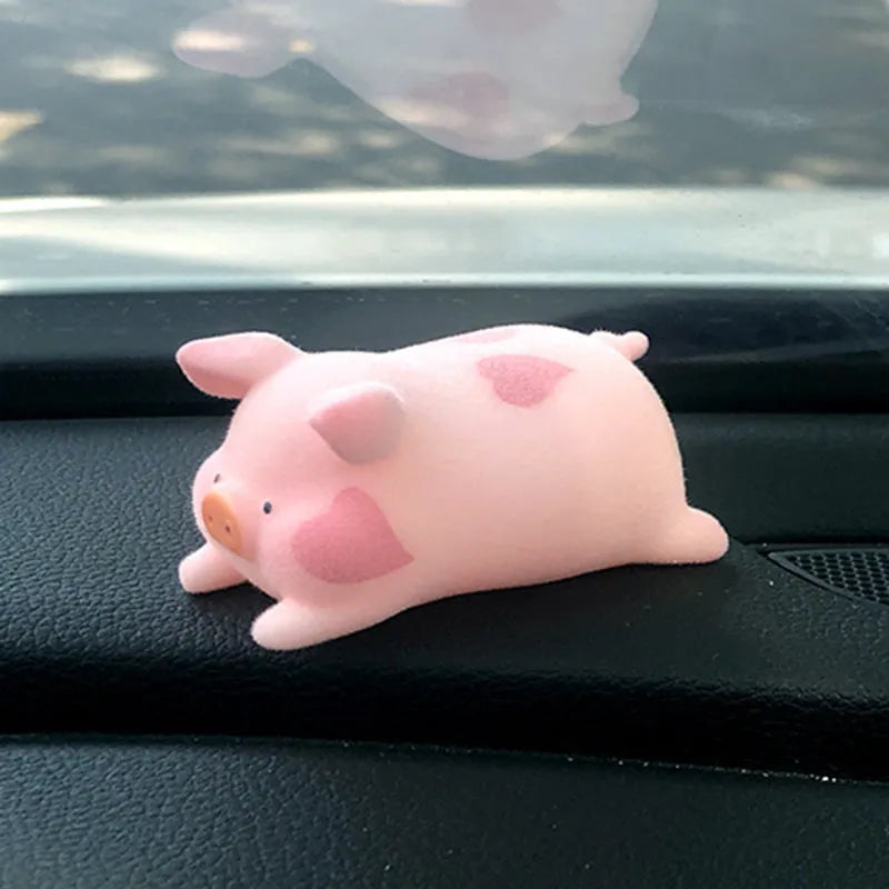 A cute resin cartoon pig figurine car dashboard decoration on a grey background.