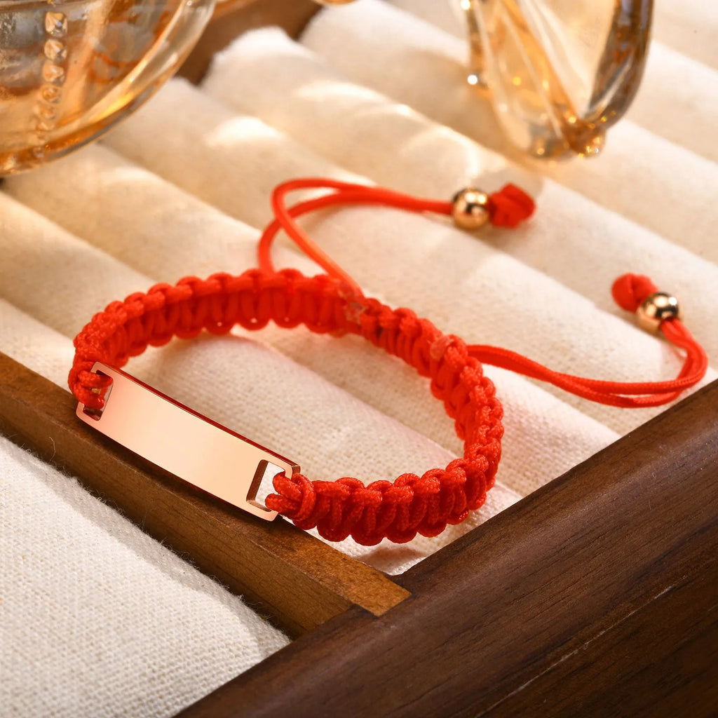 Red nylon rope woven child's bracelet with curved stainless steel brand piece in rose gold finish