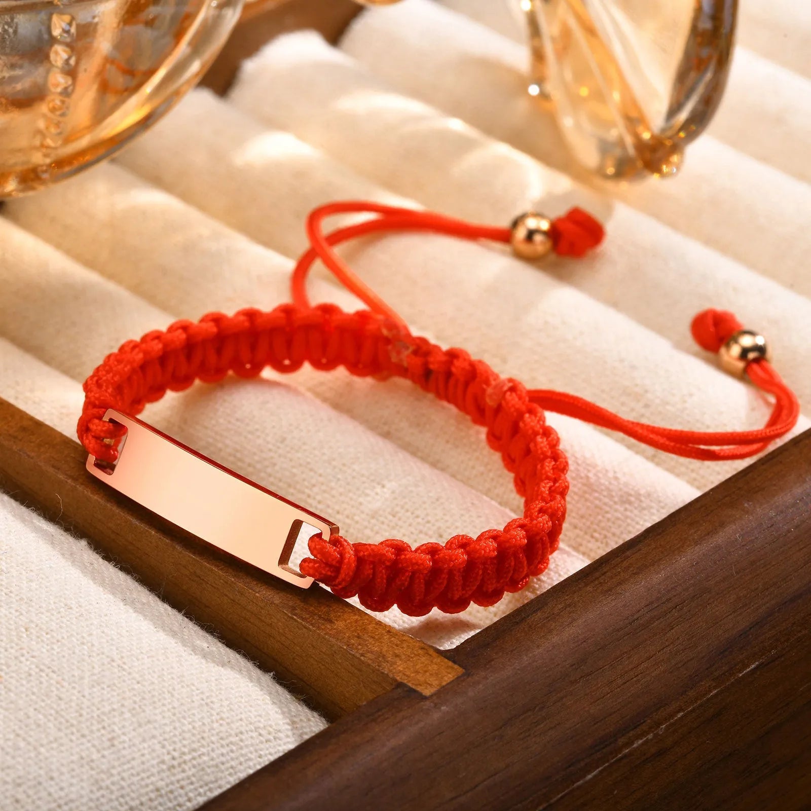 Red nylon rope woven child's bracelet with curved stainless steel brand piece in rose gold finish