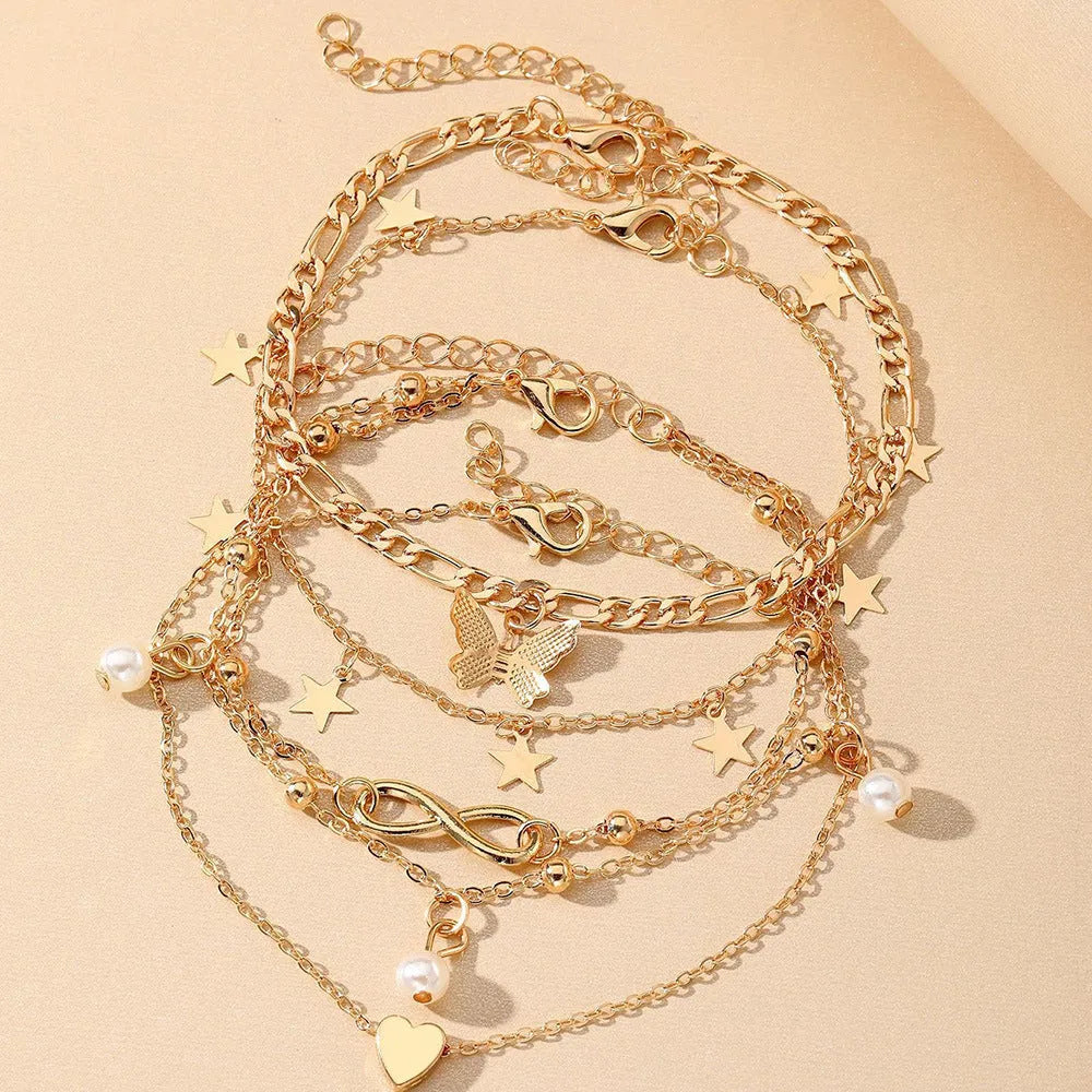 Set of four women's alloy anklets with butterfly, pearl, and heart charms.