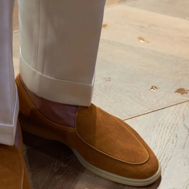 British handmade men's brown genuine leather flat loafers on a plain background.
