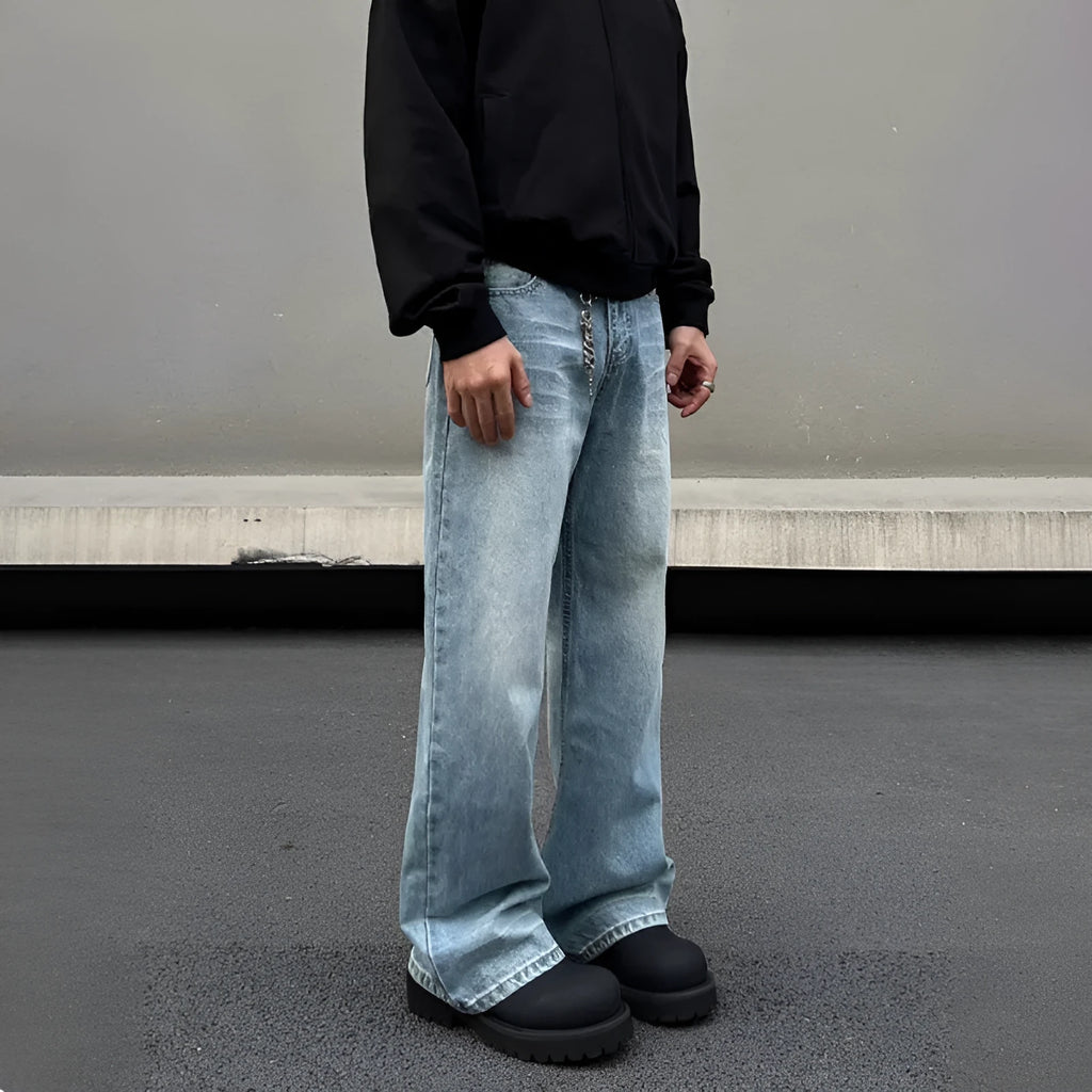 Man wearing blue straight leg jeans with whisker wash detailing and a flared leg style.
