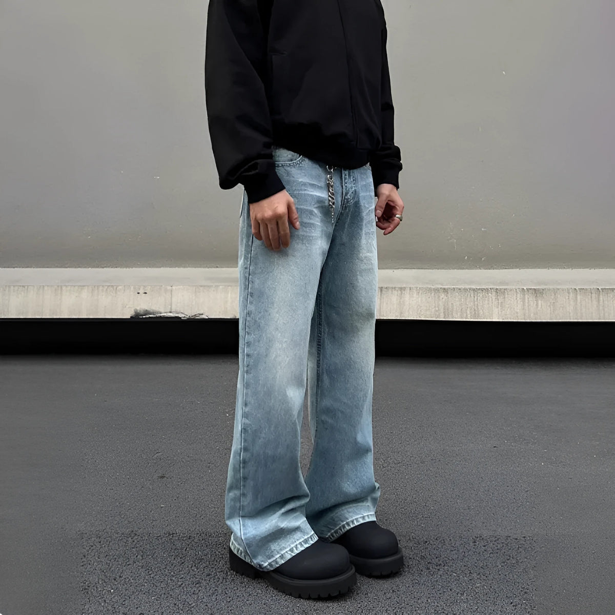 Man wearing blue straight leg jeans with whisker wash detailing and a flared leg style.