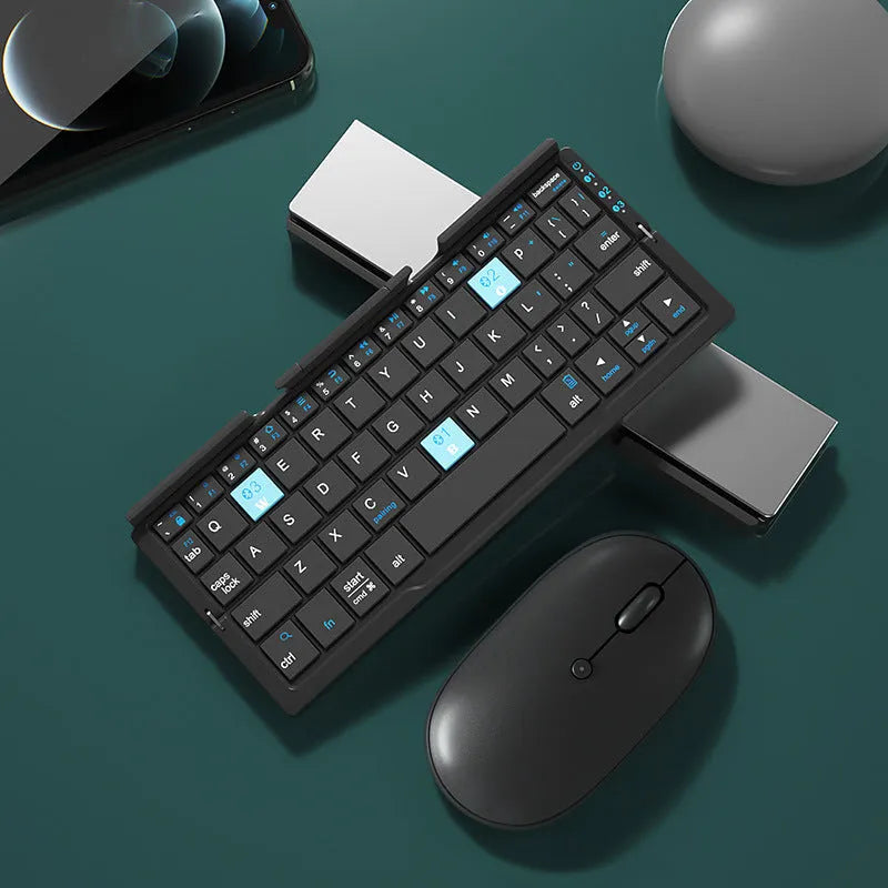 Silver white mini aluminium folding Bluetooth keyboard open next to a smartphone on its integrated stand.