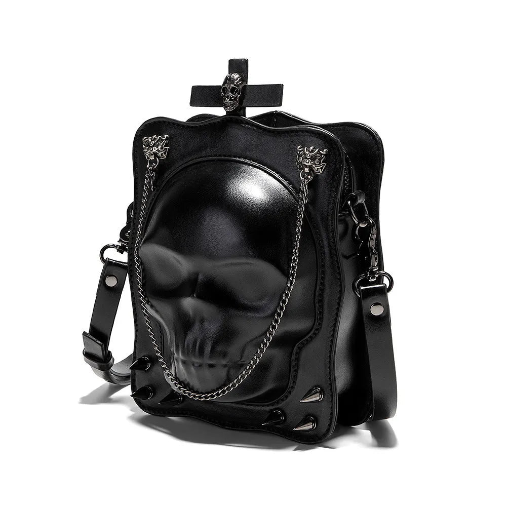 Black gothic mini square messenger bag with skull embossing, stitching, rivets, and chain details on textured PU polyester